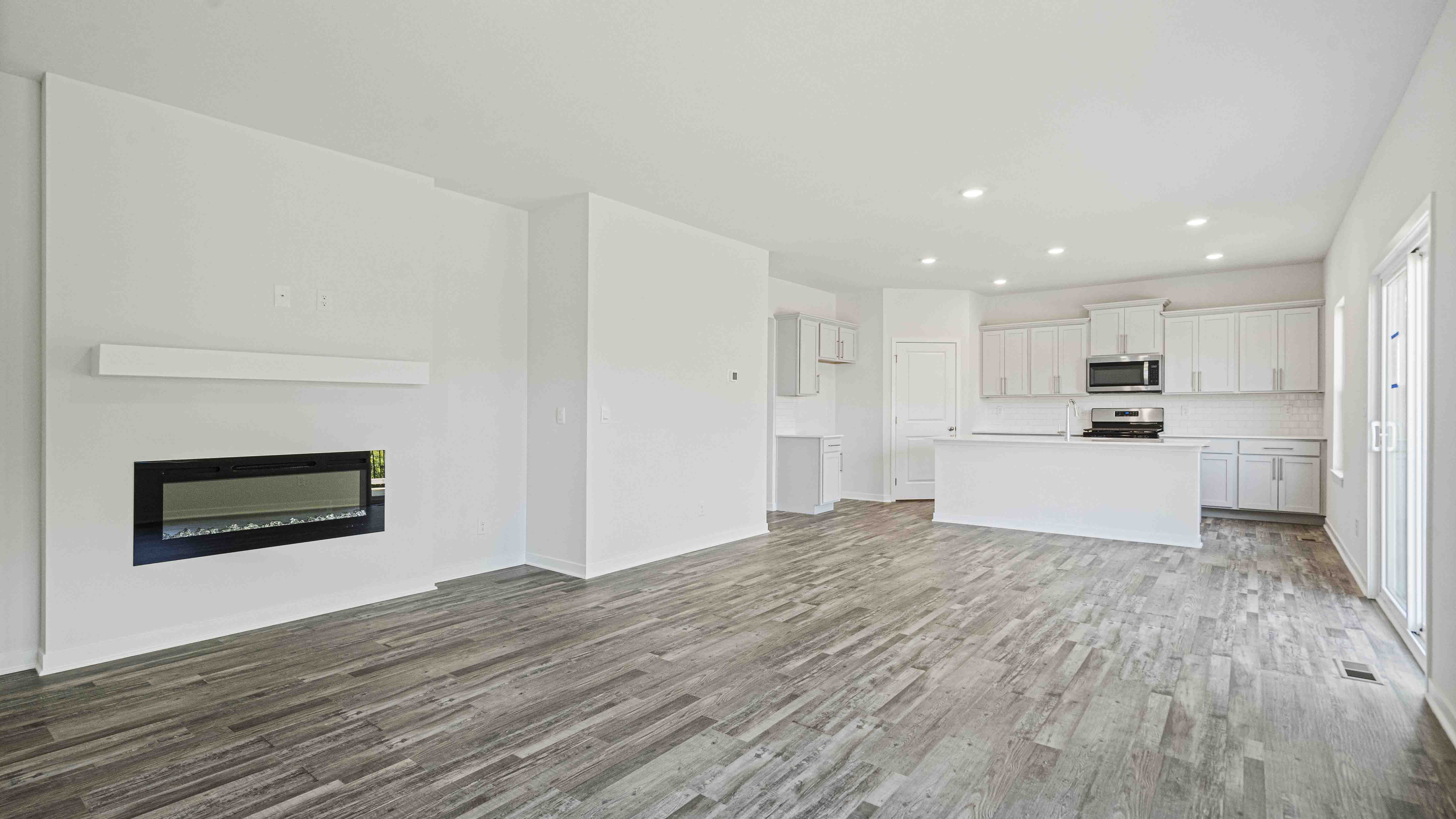 Living room beside kitchen, with electric fireplace and large windows