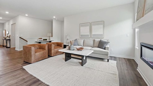 Spacious living room with brown flooring, white walls, a black fireplace and windows