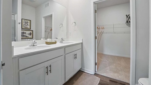 bathroom with dual vanity sinks, toilet, and a walk in shower