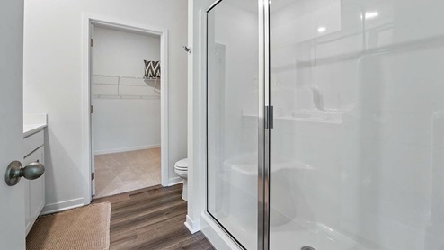 bathroom with dual vanity sinks, toilet, and a walk in shower