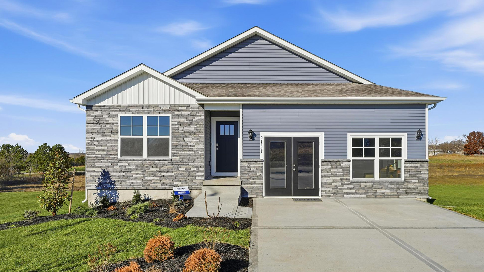 Front exterior of a home with a two car garage, blue and white siding and stone accents