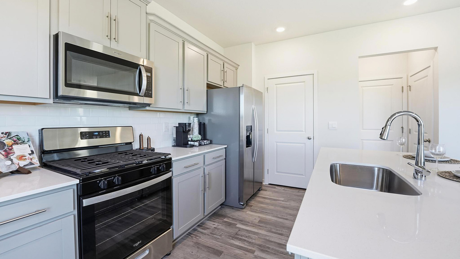 Kitchen and island with white cabinets and stainless steel appliances.