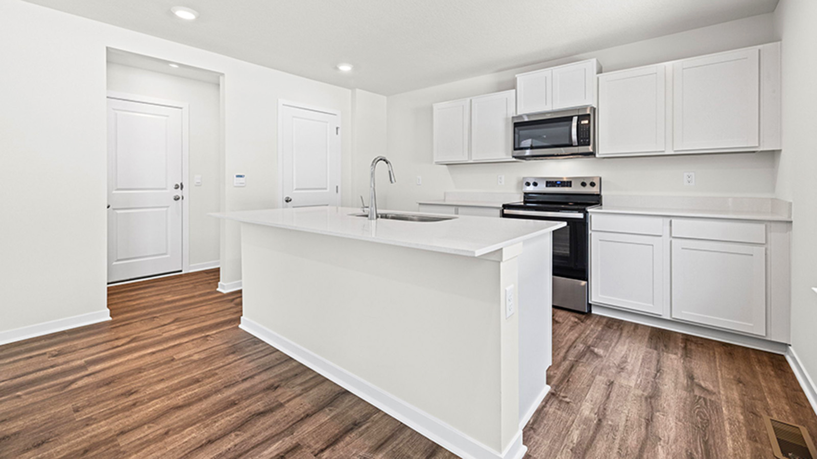 Kitchen and island with white cabinets and stainless steel appliances.