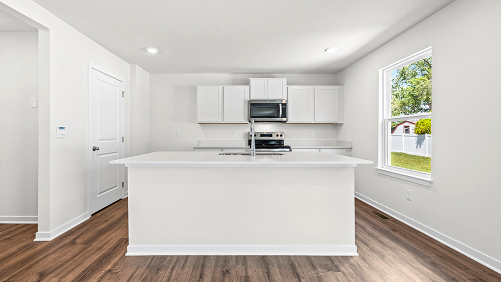 Kitchen and island with white cabinets and stainless steel appliances.