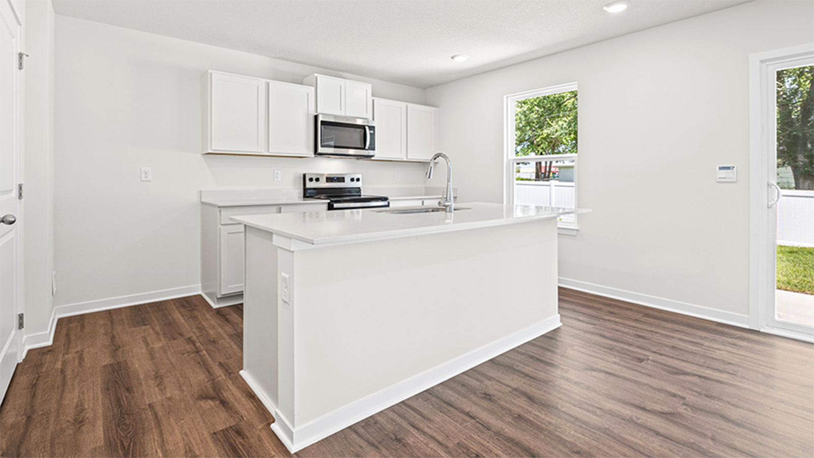 Kitchen and island with white cabinets and stainless steel appliances.