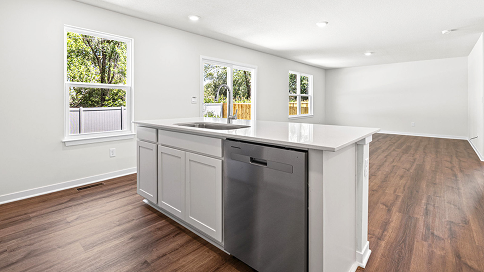 Kitchen and island with white cabinets and stainless steel appliances.