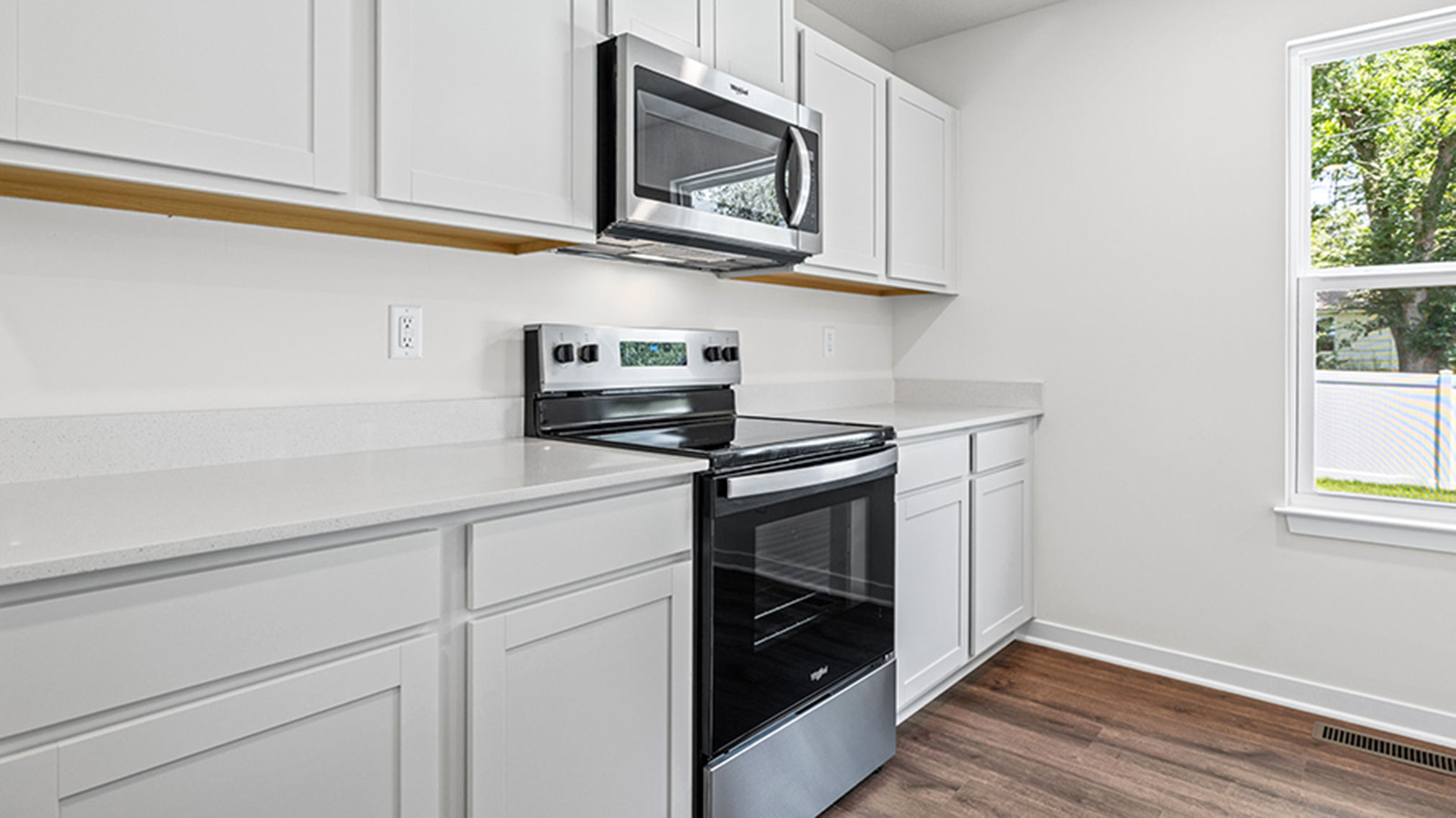 Kitchen and island with white cabinets and stainless steel appliances.