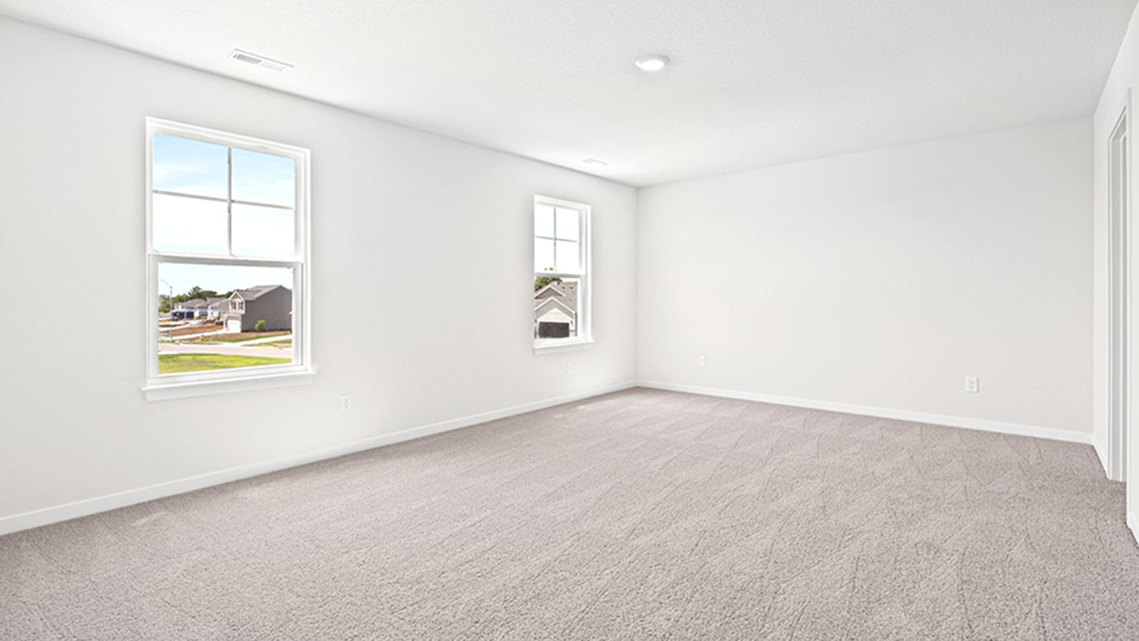 Carpeted primary bedroom with large windows and seating area.