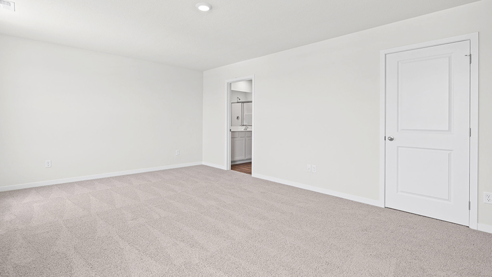 Carpeted primary bedroom with large windows and seating area.