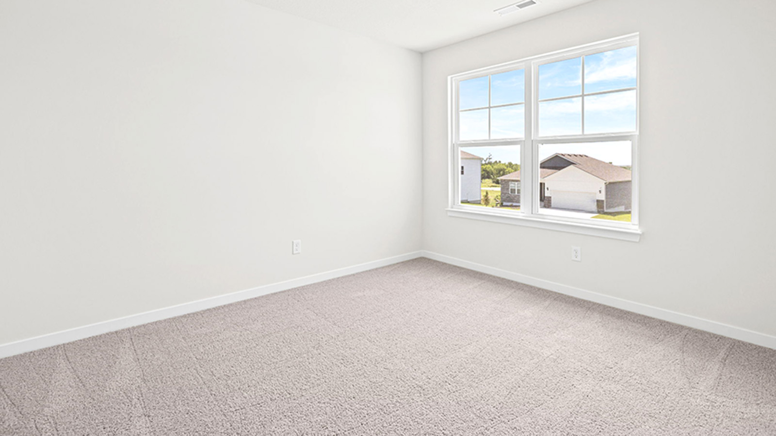 Carpeted bedroom with large window.