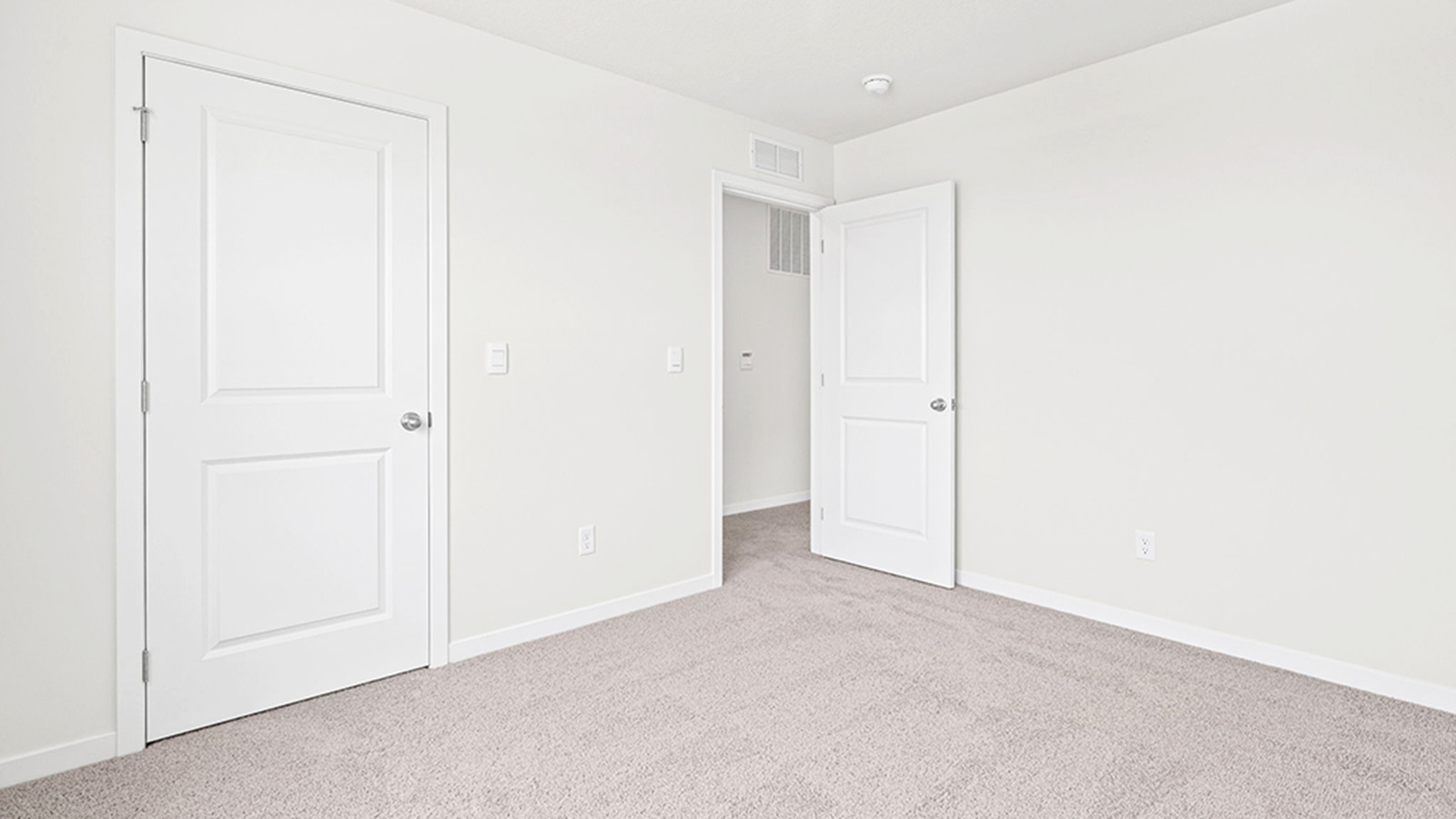 Carpeted bedroom with large window.