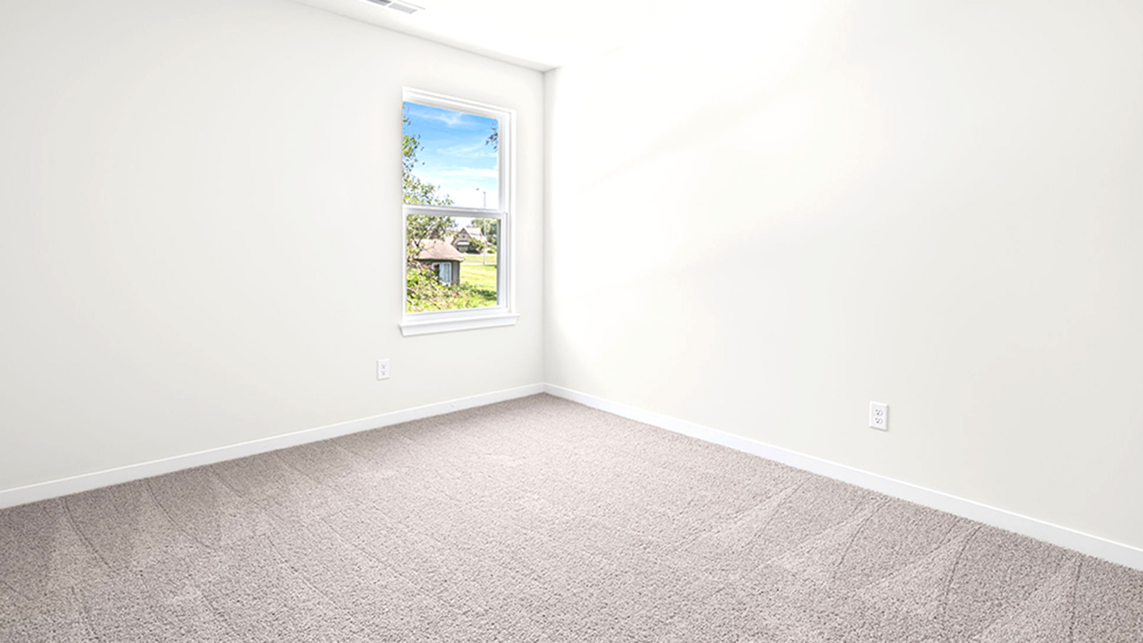 Carpeted bedroom with large window.