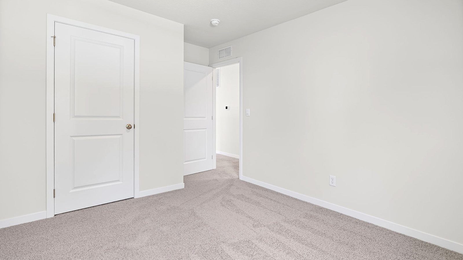 Carpeted bedroom with large window.