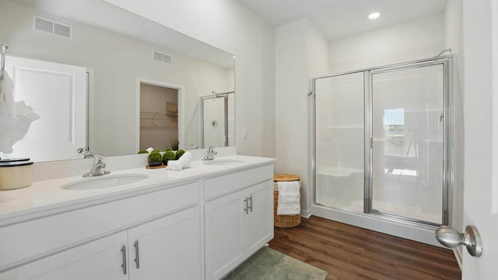 Primary bathroom with double sink vanity  and standing glass door shower.