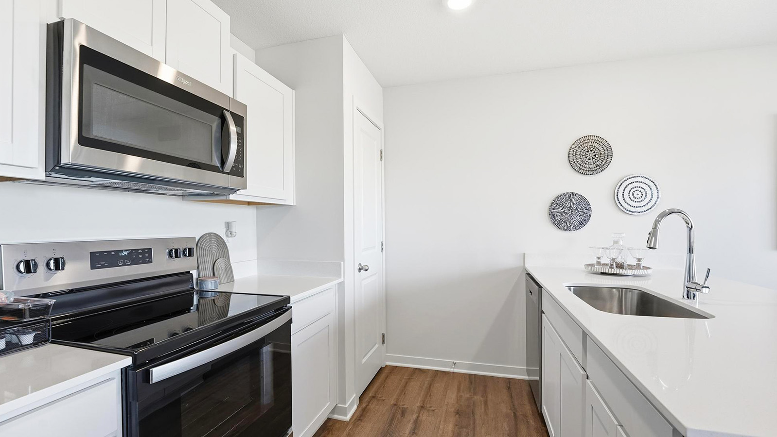 Open-concept kitchen with white quartz counters and cabinets, and stainless steel appliances