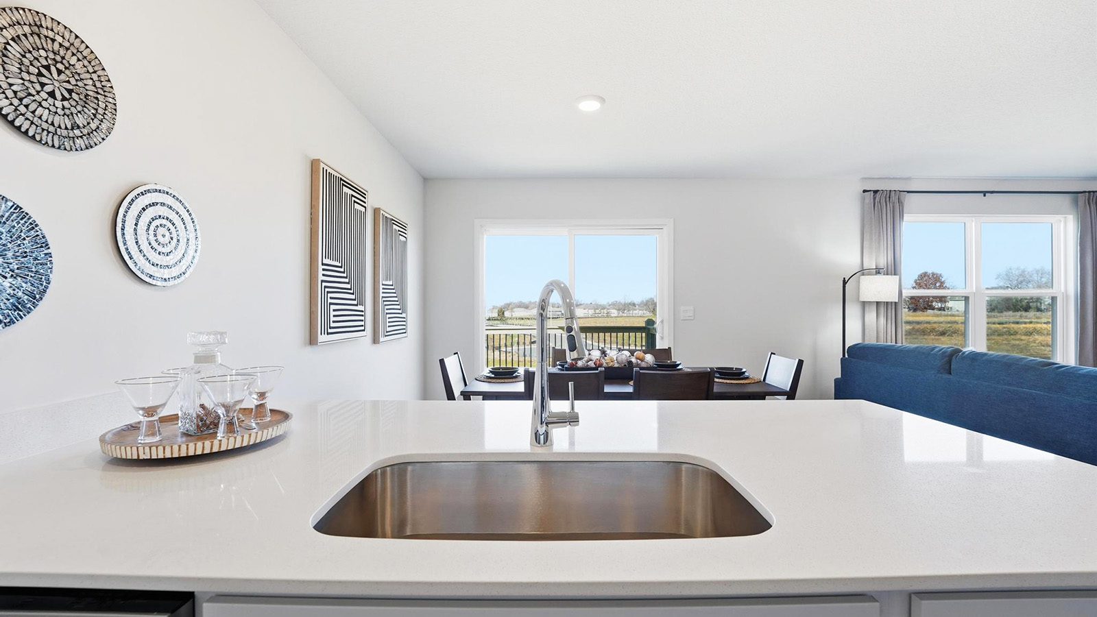 Open-concept kitchen with white quartz counters and cabinets, and stainless steel appliances