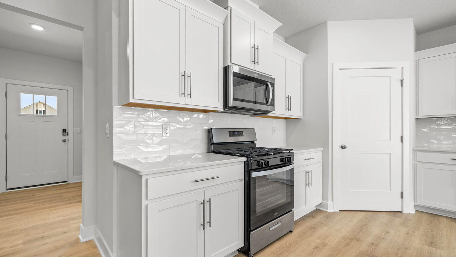 Kitchen and island with white cabinets, tile backsplash, and stainless steel appliances
