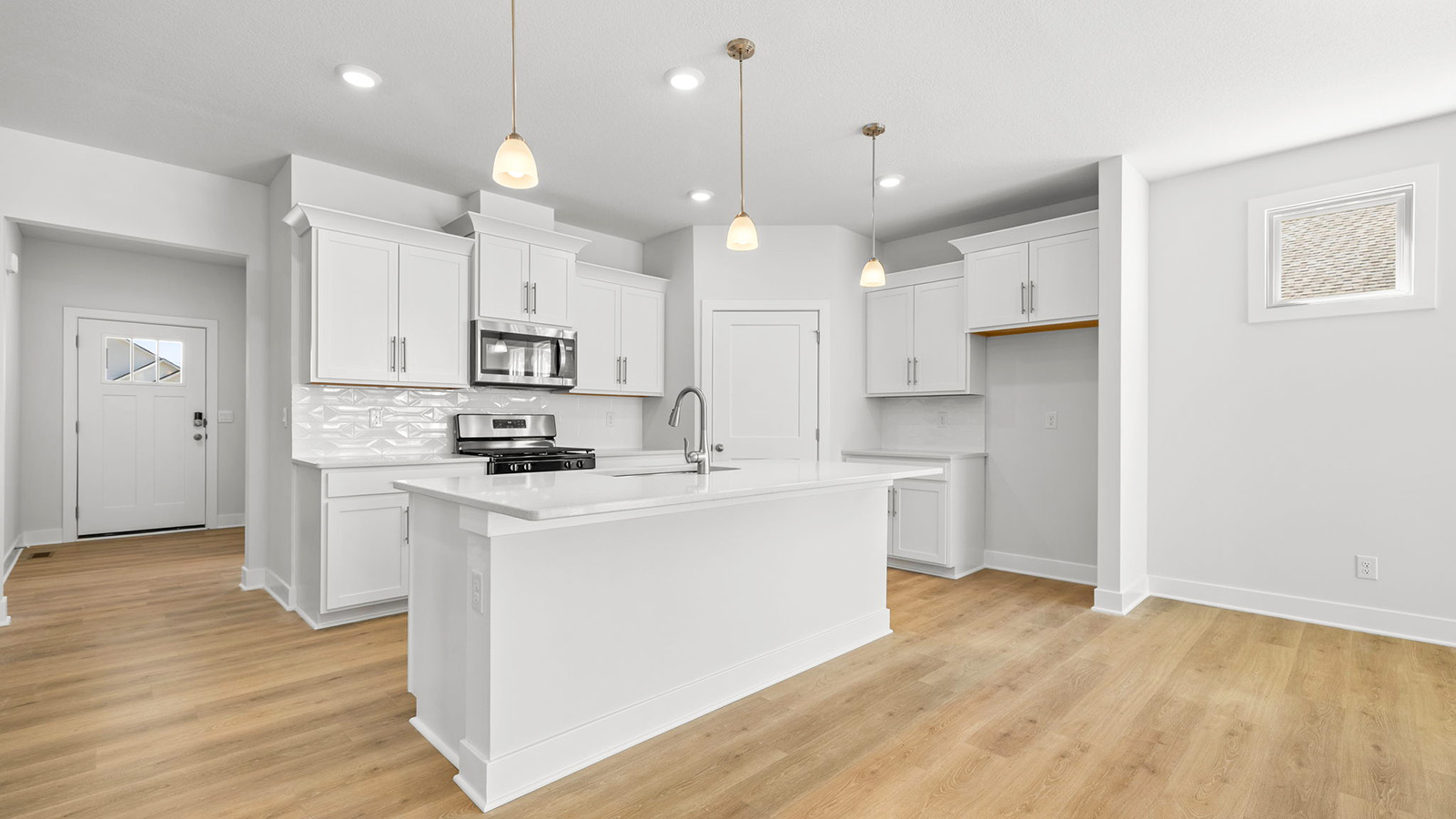 Kitchen and island with white cabinets, tile backsplash, and stainless steel appliances