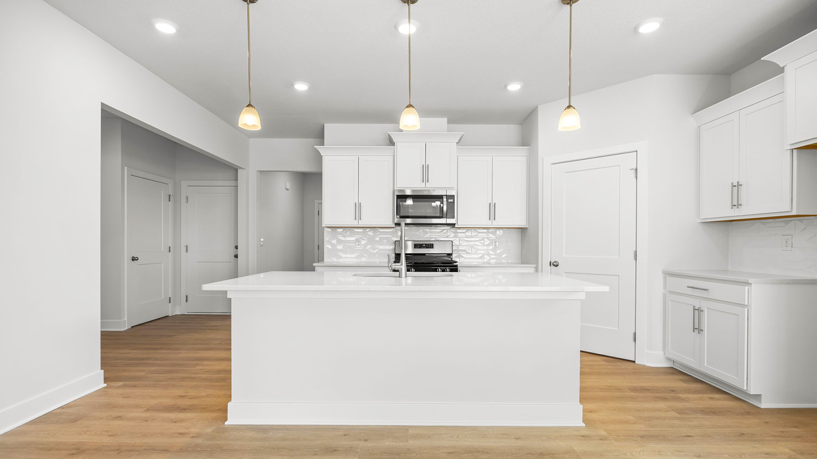 Kitchen and island with white cabinets, tile backsplash, and stainless steel appliances
