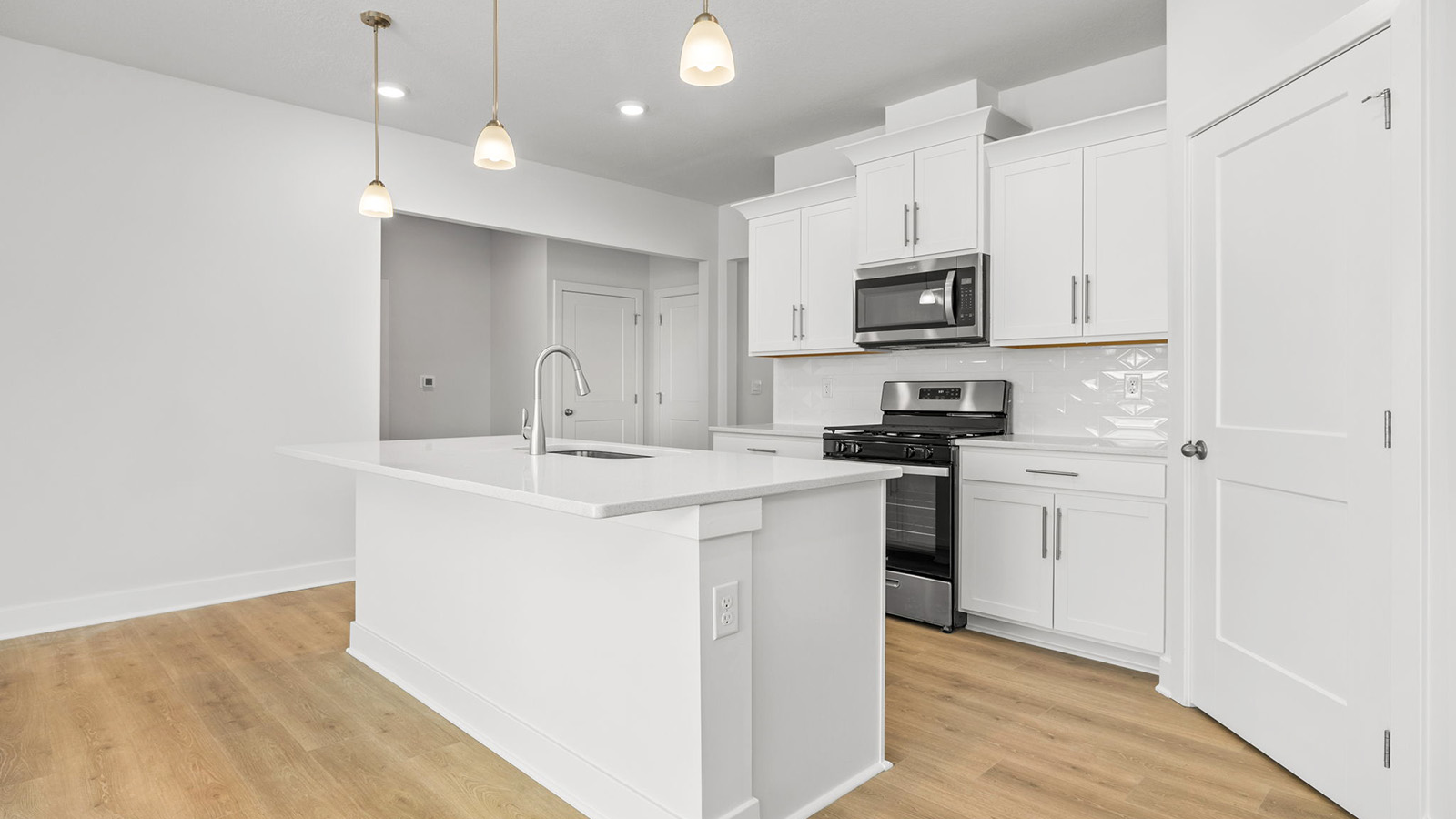 Kitchen and island with white cabinets, tile backsplash, and stainless steel appliances