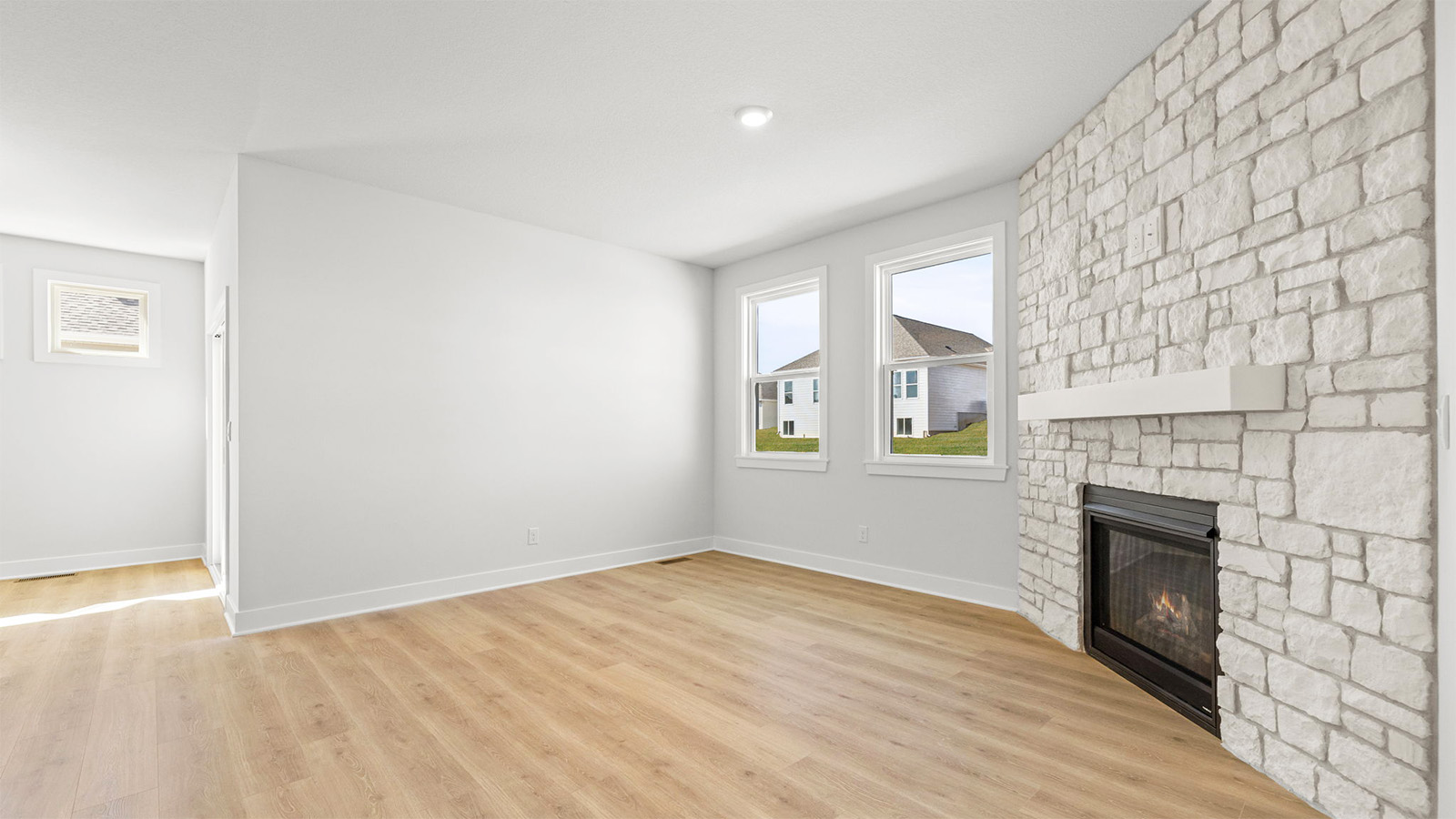 Living room beside kitchen, with stone fireplace and large window