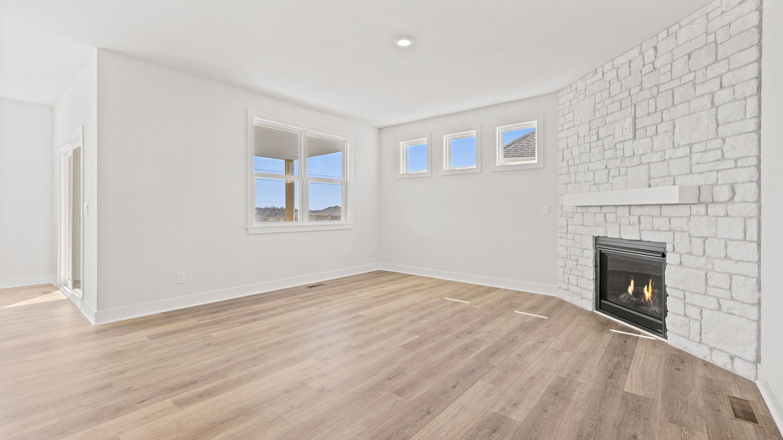 Living room beside kitchen, with stone fireplace and large windows