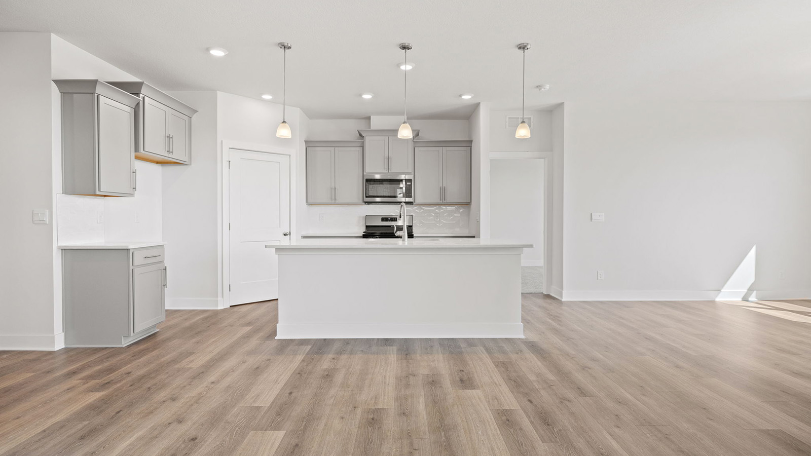 Kitchen and island with white cabinets, tile backsplash, and stainless steel appliances
