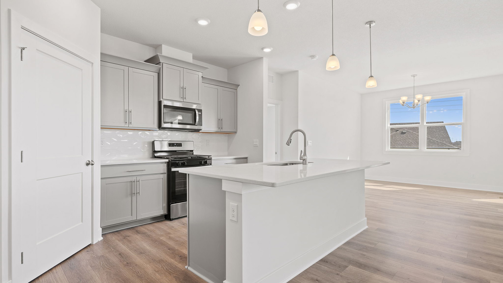 Kitchen and island with white cabinets, tile backsplash, and stainless steel appliances