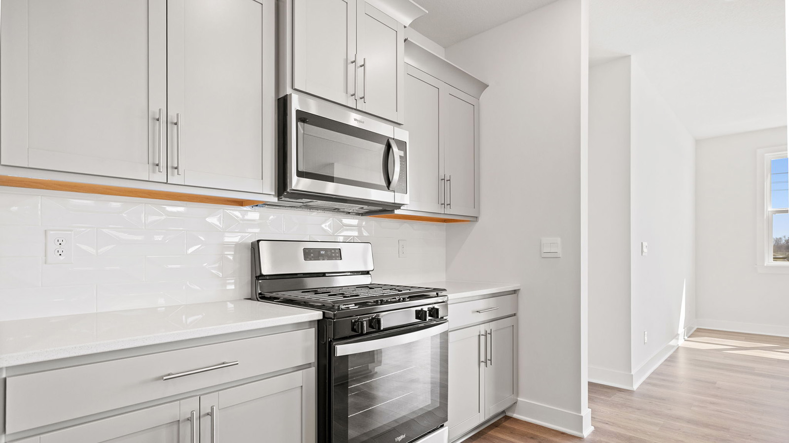 Kitchen and island with white cabinets, tile backsplash, and stainless steel appliances