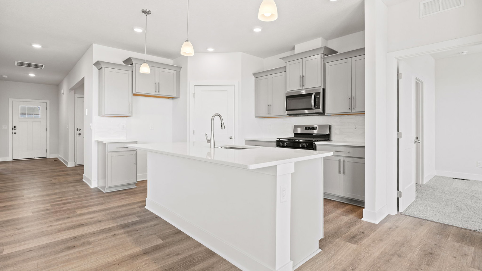 Kitchen and island with white cabinets, tile backsplash, and stainless steel appliances