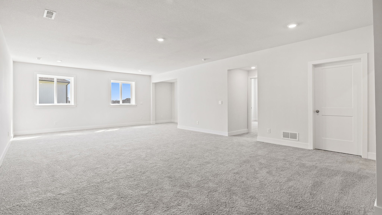 Carpeted basement rec room with large windows