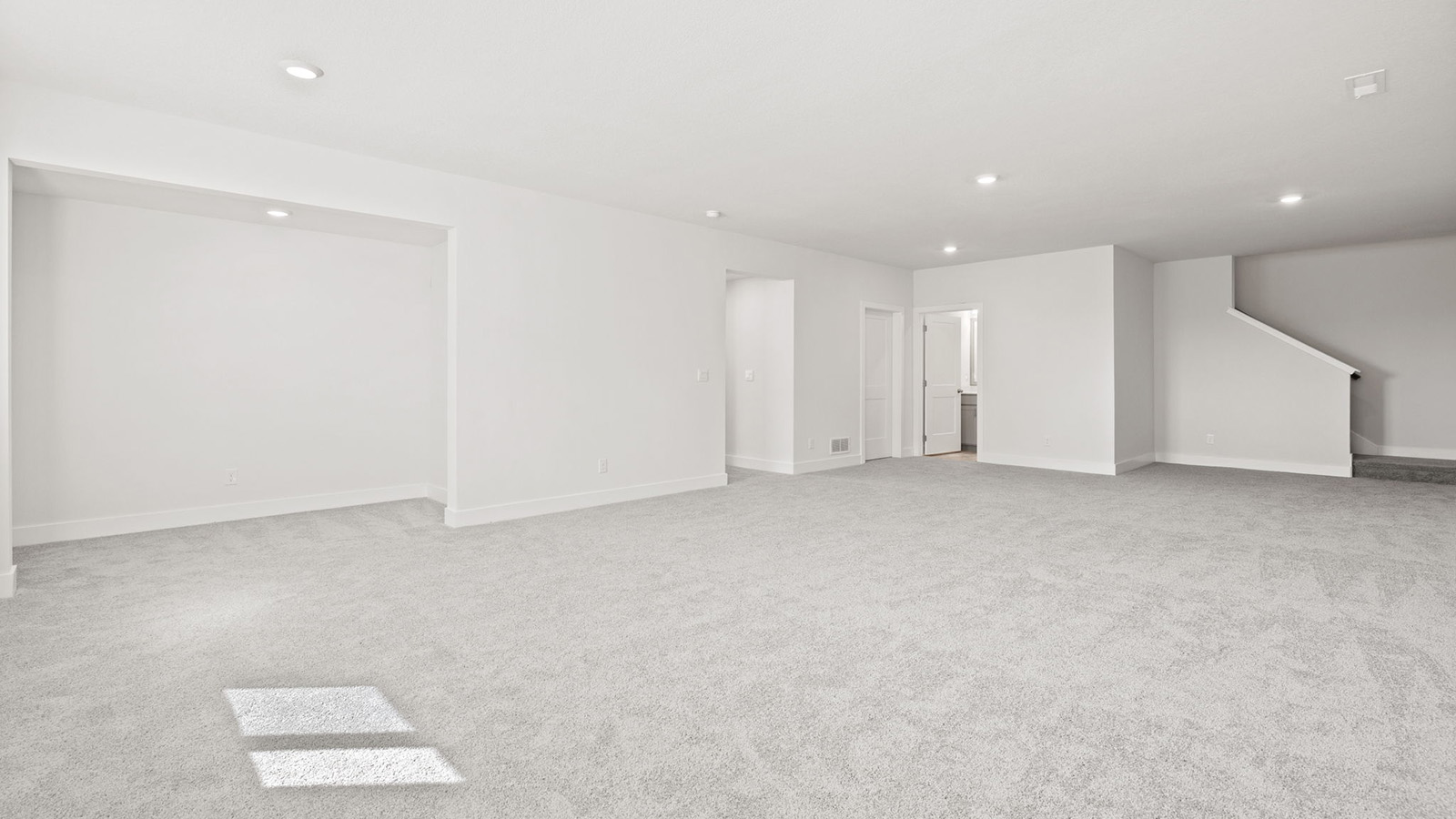 Carpeted basement rec room with large windows
