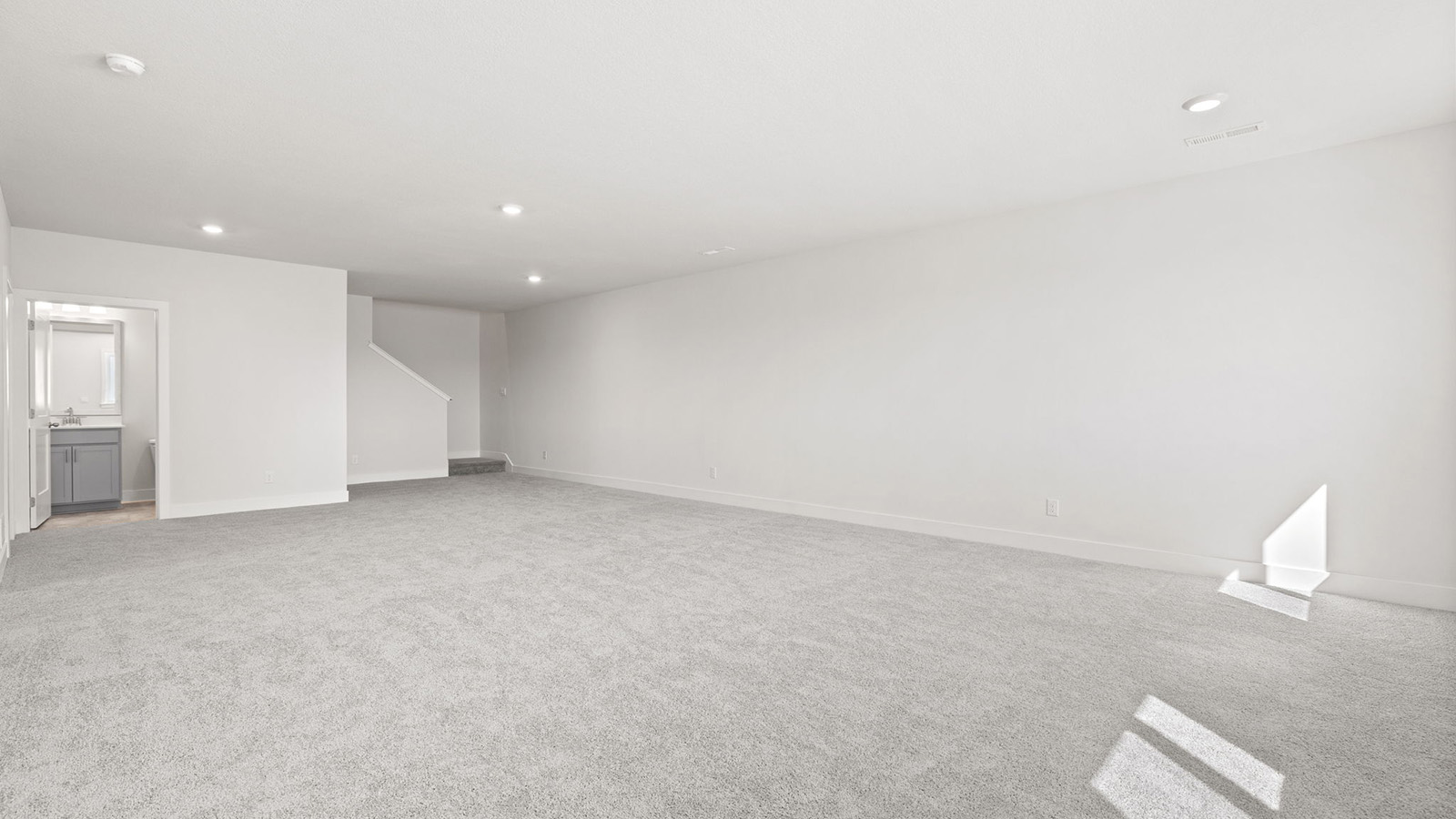 Carpeted basement rec room with large windows