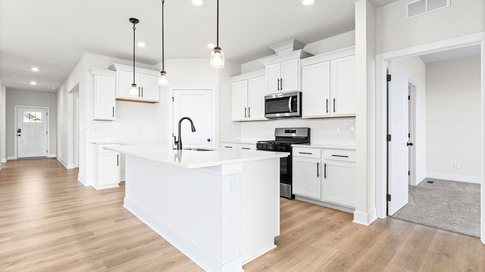 Kitchen and island with white cabinets, tile backsplash, and stainless steel appliances