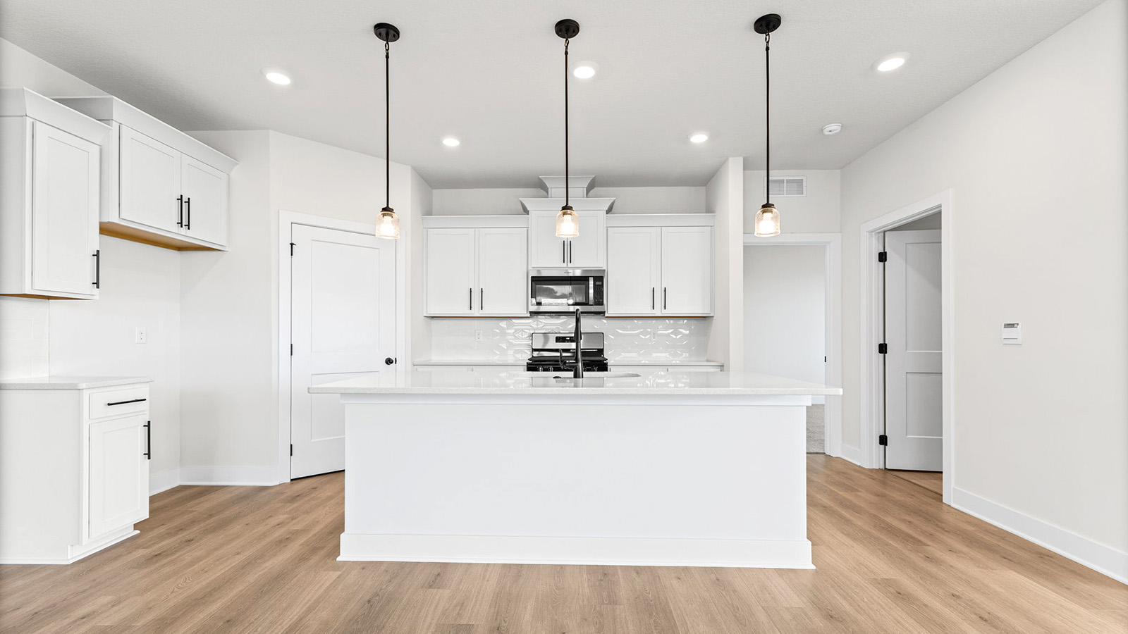 Kitchen and island with white cabinets, tile backsplash, and stainless steel appliances
