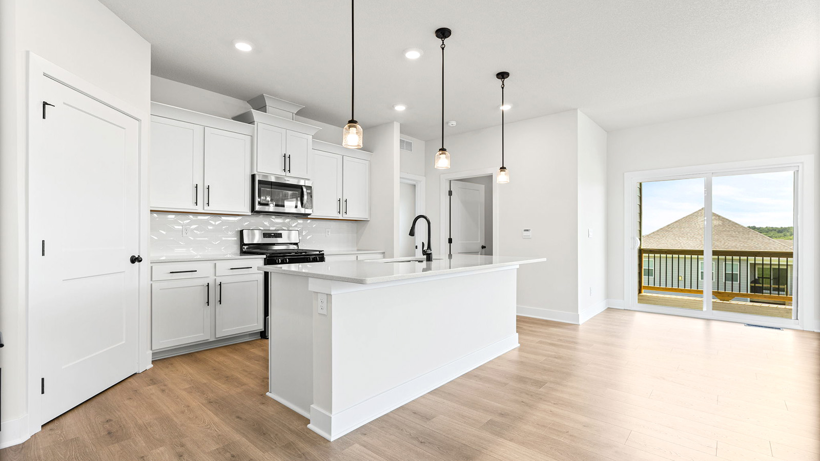 Kitchen and island with white cabinets, tile backsplash, and stainless steel appliances