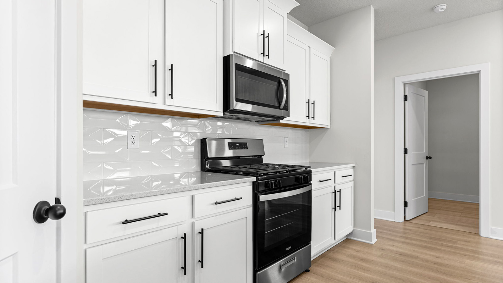 Kitchen and island with white cabinets, tile backsplash, and stainless steel appliances