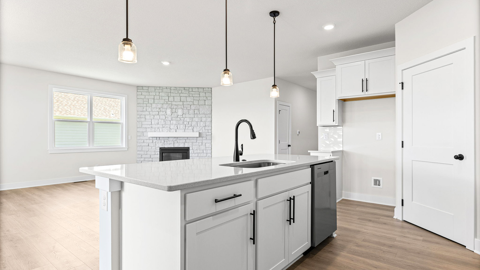 Kitchen and island with white cabinets, tile backsplash, and stainless steel appliances