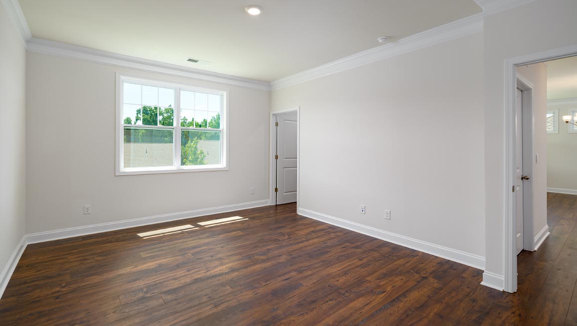 Primary bedroom with wood floors, and large window