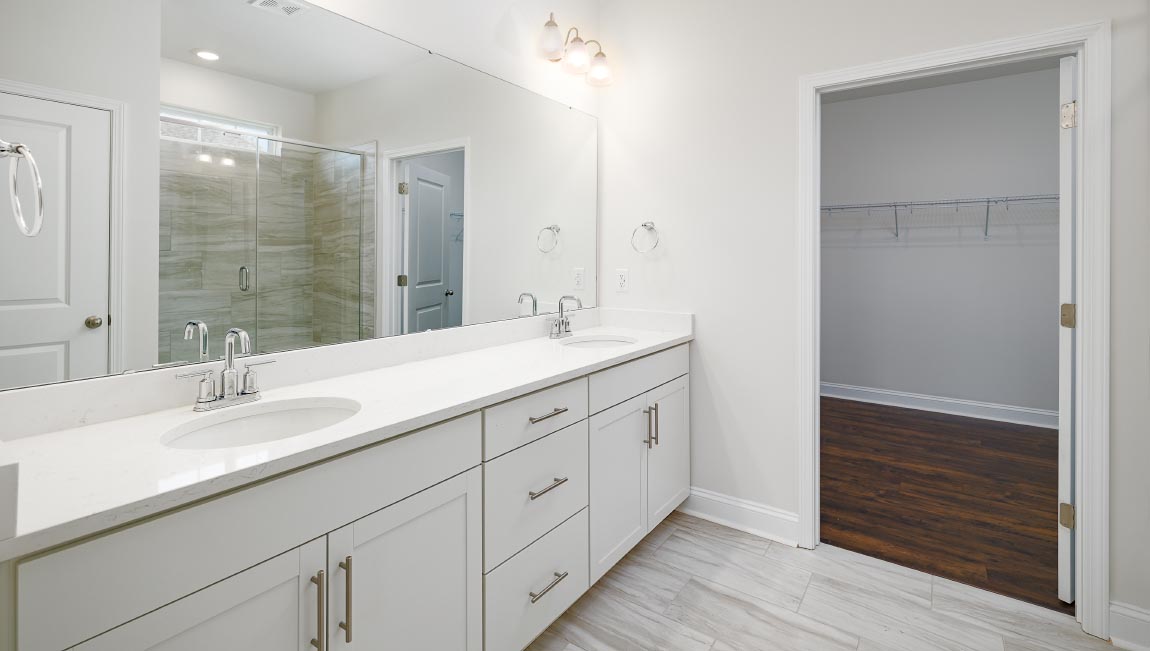 Primary bathroom with double sinks, and white cabinets