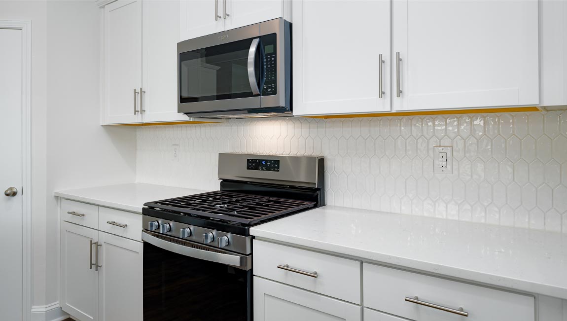 Kitchen and island with wood floors, white cabinets, breakfast area at island bar, and stainless steel appliances