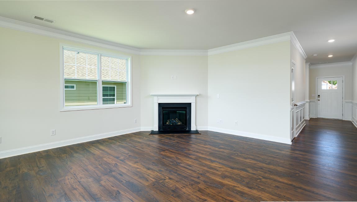 Open family room in view of dining room, with wood floors, large window and fireplace