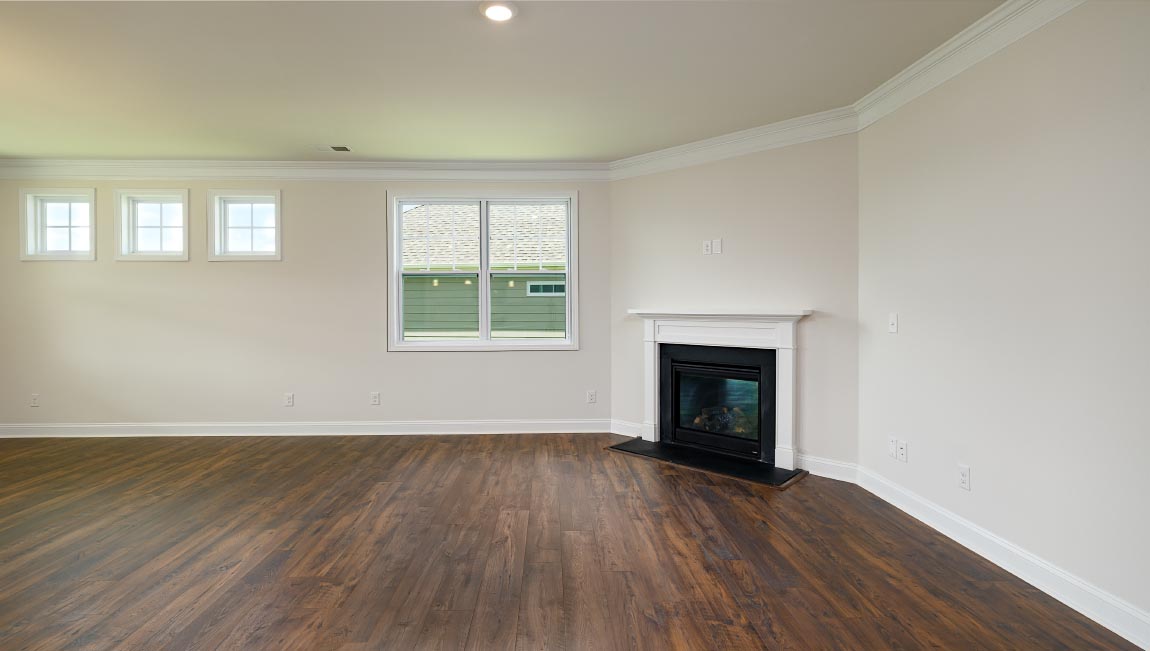 Open family room in view of dining room, with wood floors, large window and fireplace
