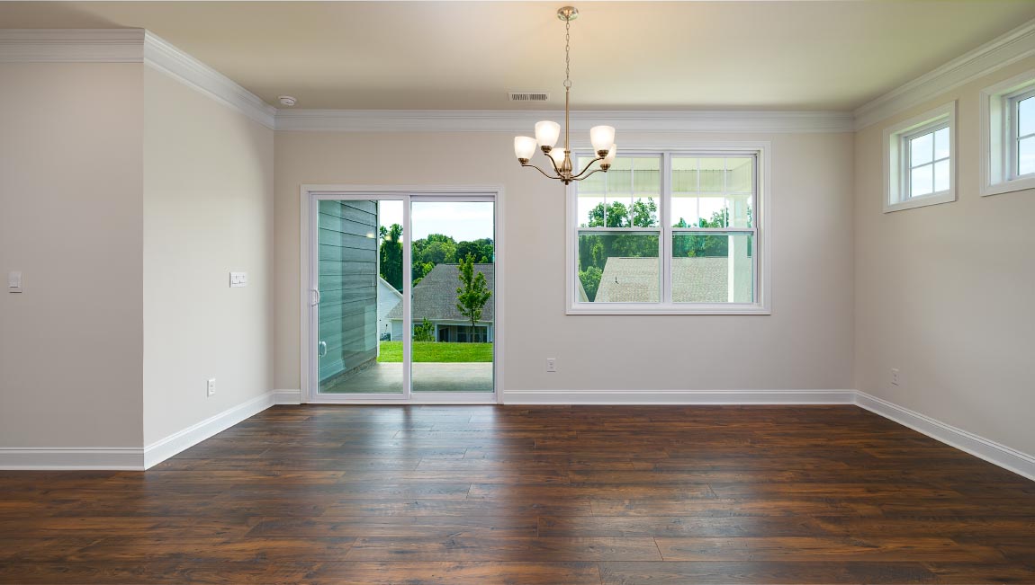 Open family room in view of dining room, with wood floors, large window and fireplace