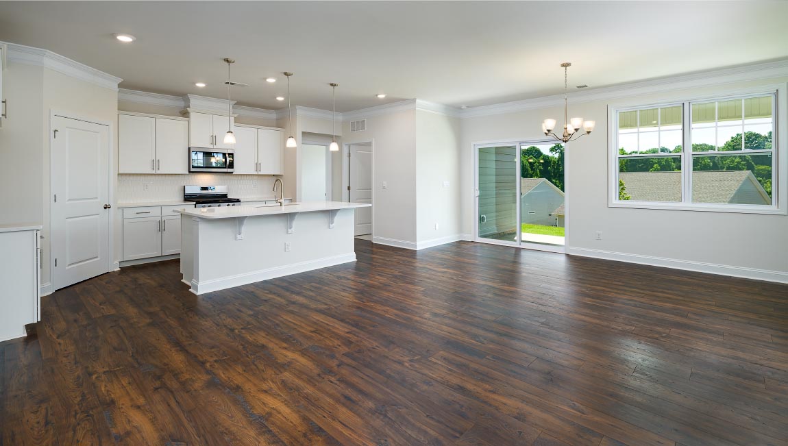 Open family room in view of dining room, with wood floors, large window and fireplace