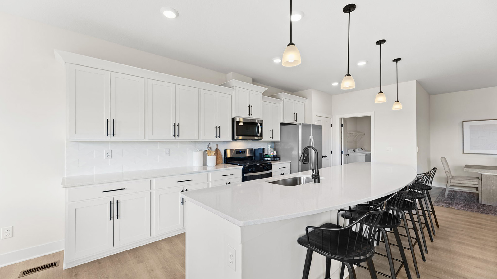 Kitchen and island with white cabinets, tile backsplash, and stainless steel appliances