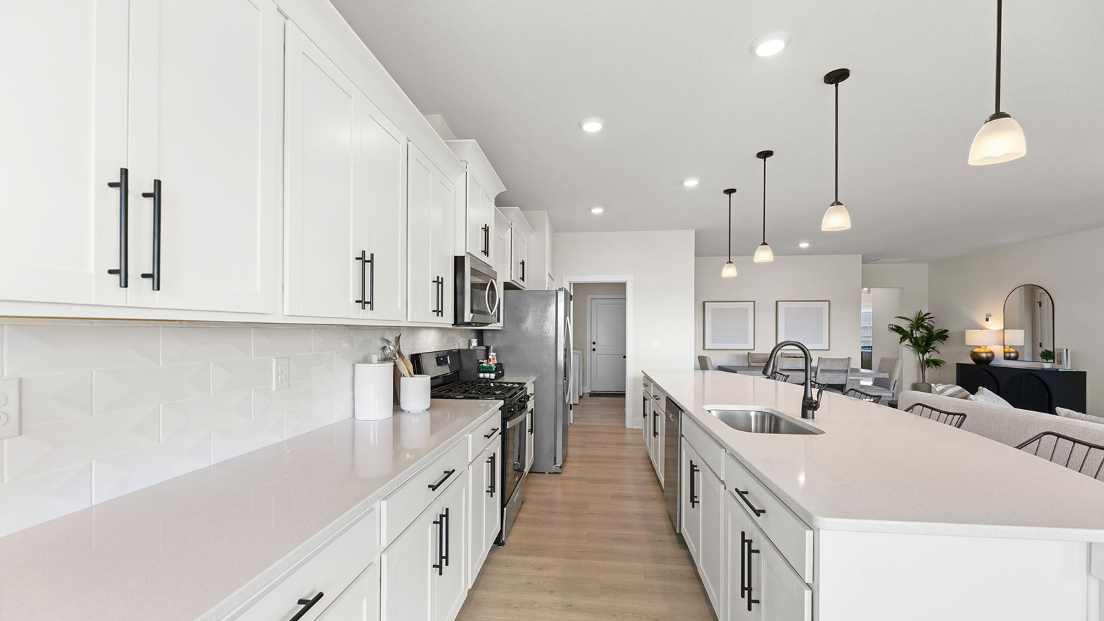 Kitchen and island with white cabinets, tile backsplash, and stainless steel appliances