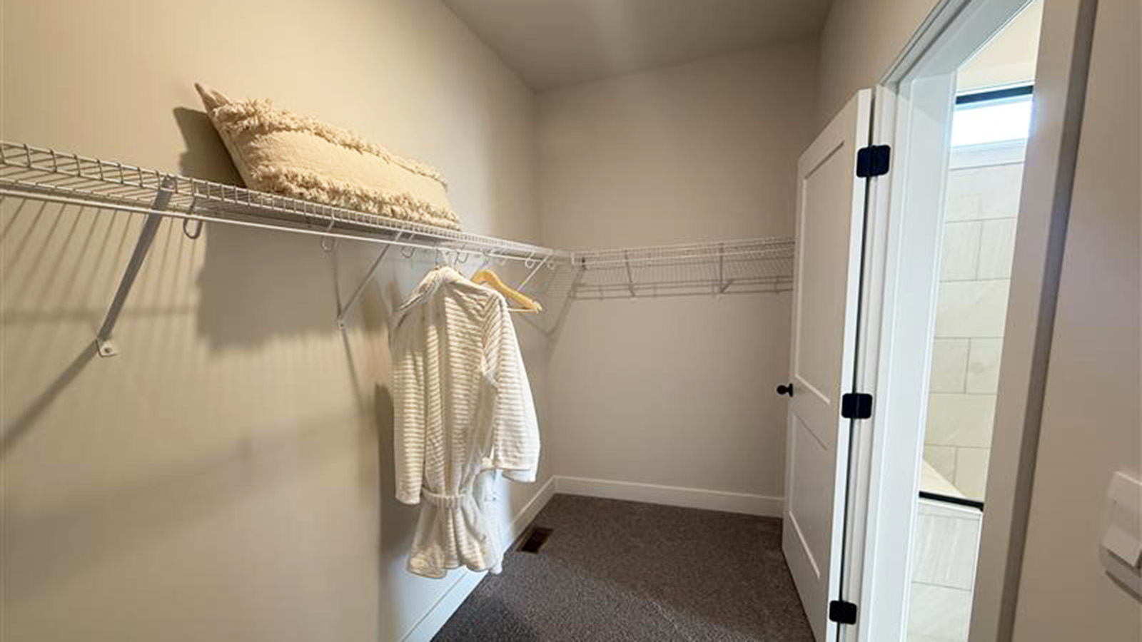 Carpeted primary walk-in closet