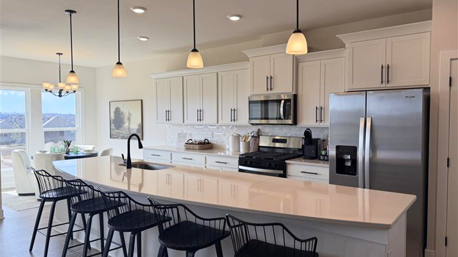 Kitchen with large island, quartz countertops, tile backsplash and stainless steel apliances