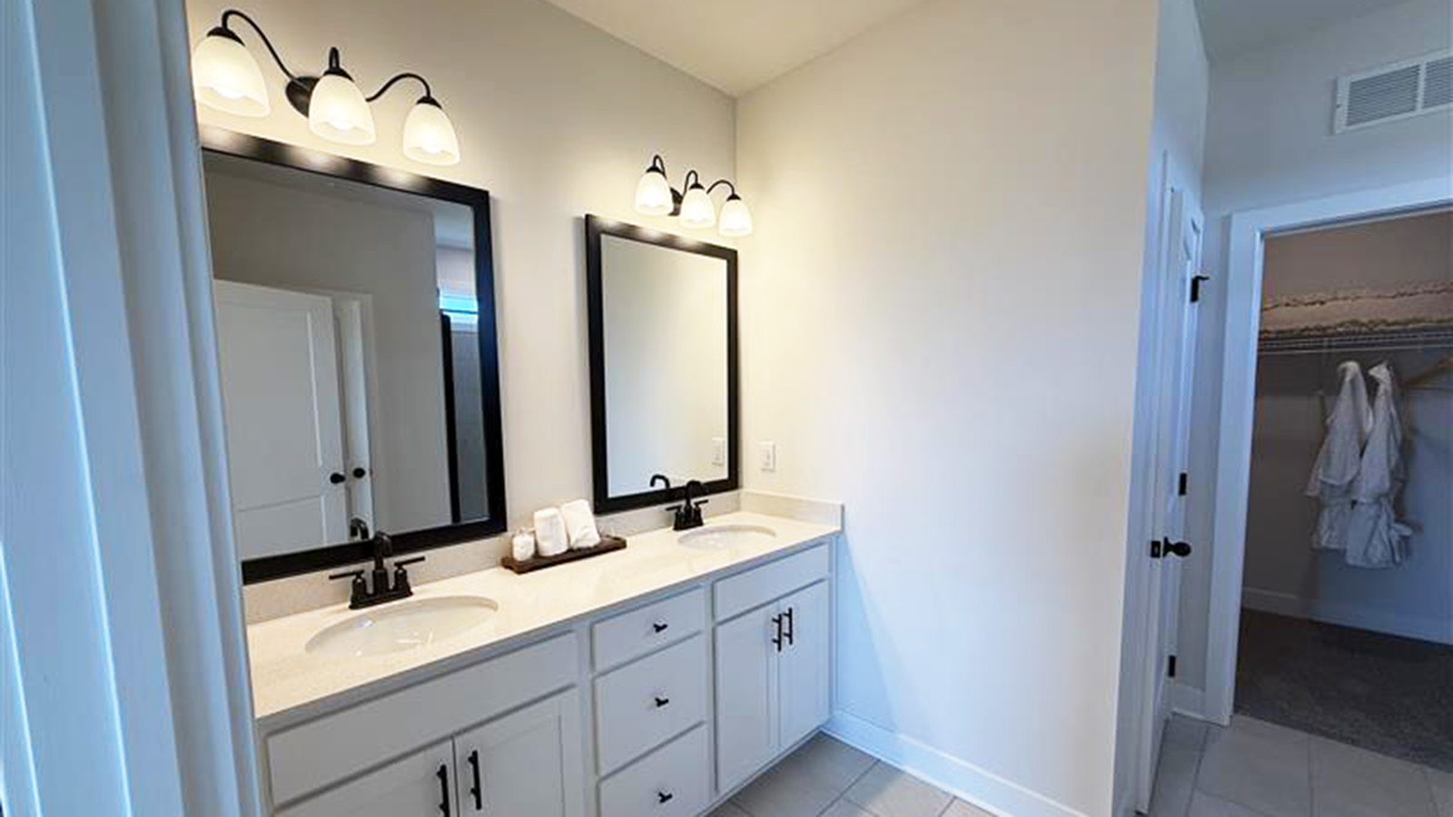 Primary bathroom with dual vanities and tile walk-in shower with glass walls.